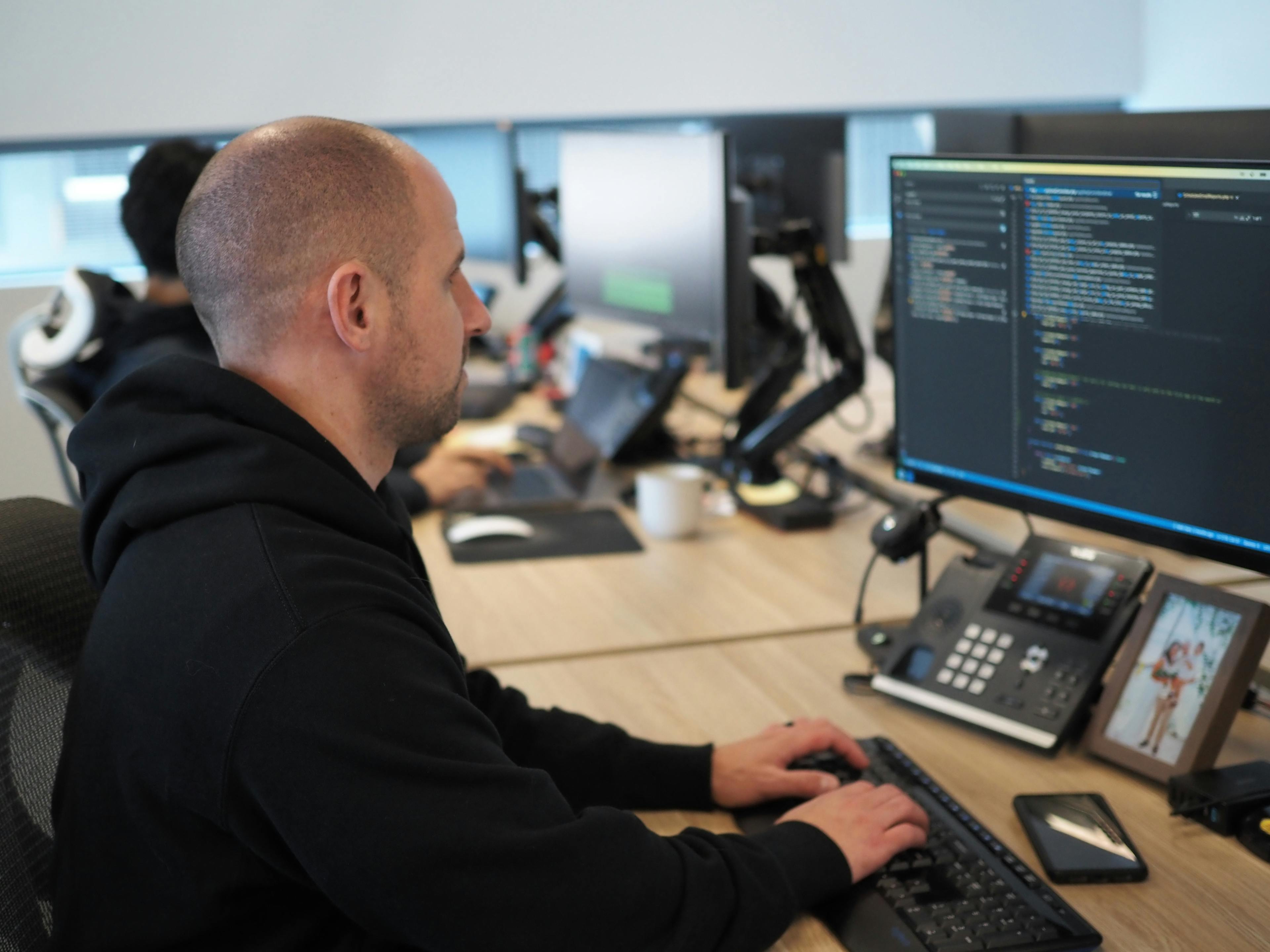 a man is sitting at a desk typing on a laptop computer .