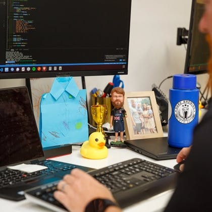 a man is sitting at a desk typing on a laptop computer .