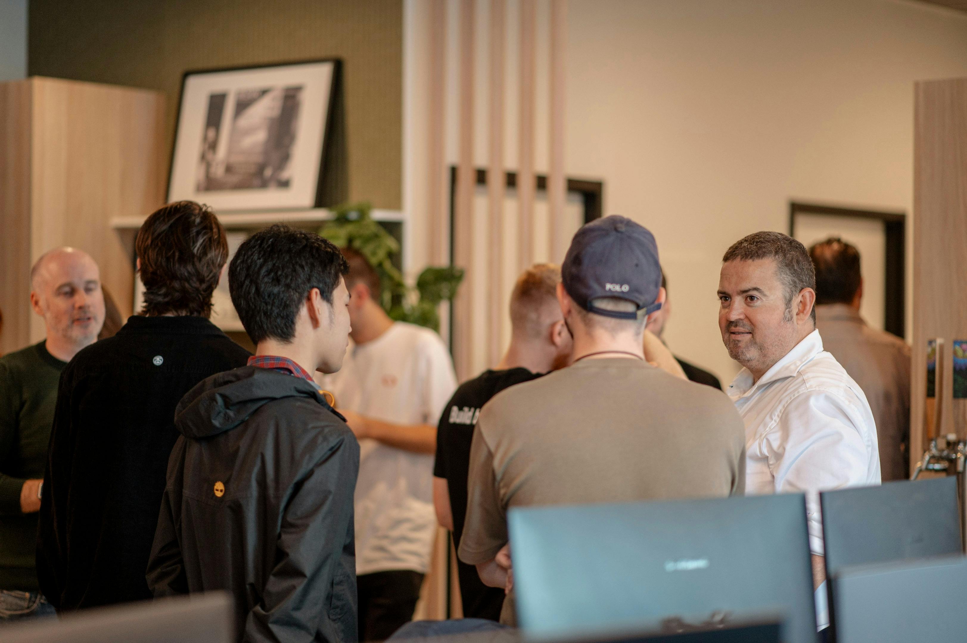 a group of men are standing in a room talking to each other .