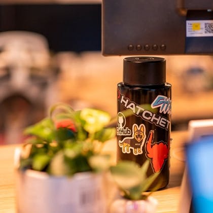 a bottle of water is sitting on a desk next to a potted plant .