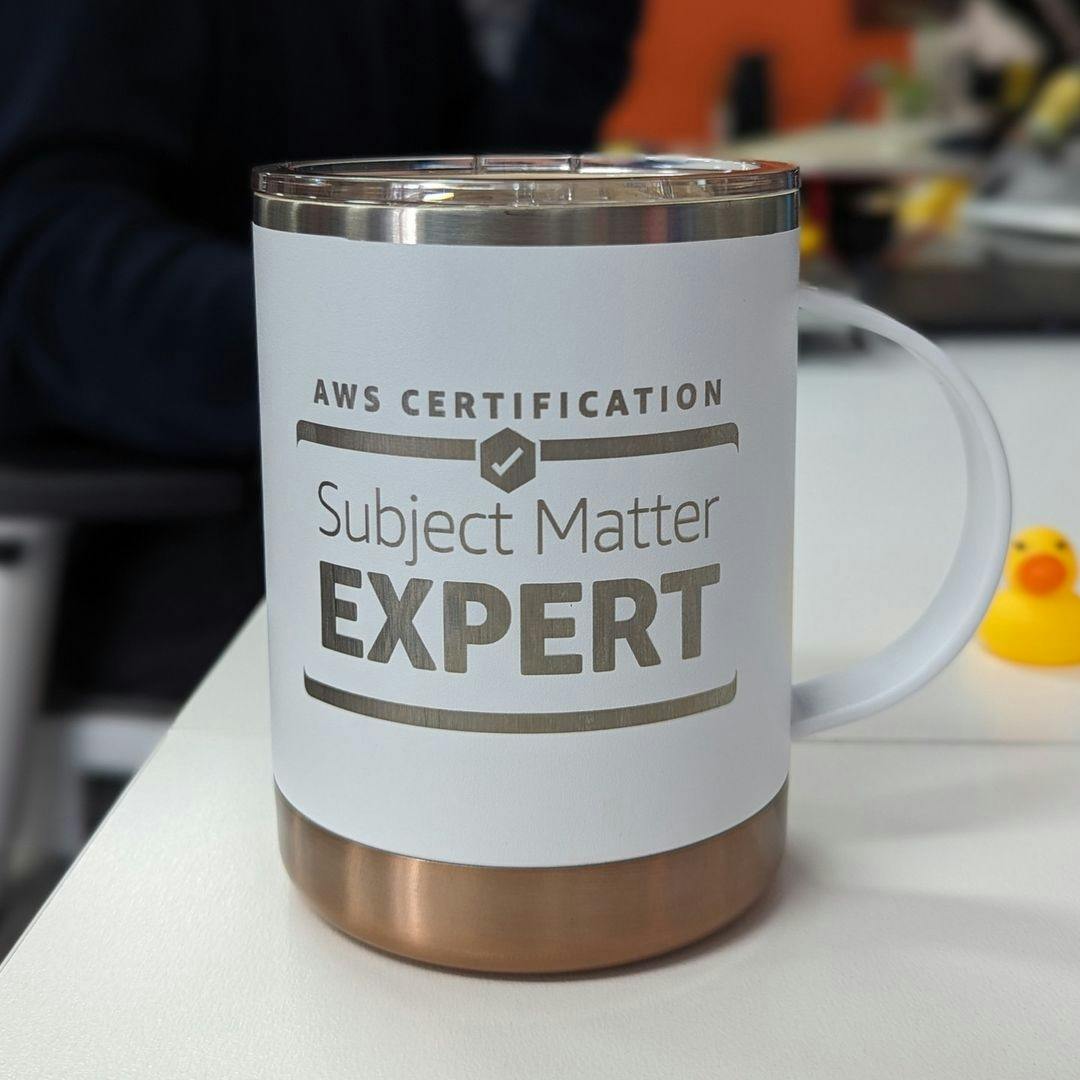 a white mug that says aws certification subject matter expert is sitting on a table .